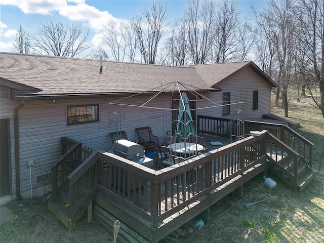 back of property with a wooden deck and roof with shingles