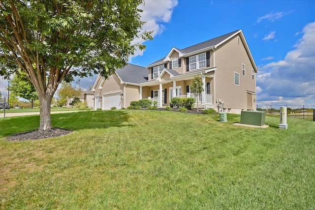 view of front of house featuring a front lawn, an attached garage, and covered porch