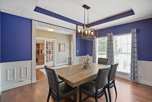 dining area featuring a tray ceiling, hardwood / wood-style flooring, and wainscoting