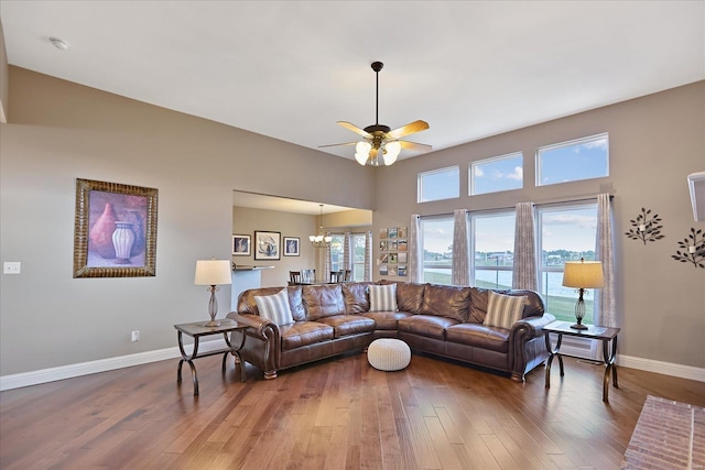 living area with ceiling fan with notable chandelier, wood finished floors, and baseboards