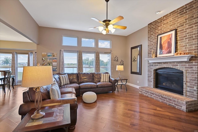 living area featuring baseboards, plenty of natural light, wood finished floors, and a fireplace