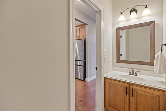 bathroom featuring vanity, wood finished floors, and baseboards