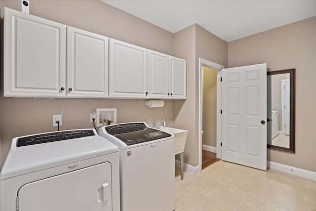 laundry room featuring a sink, baseboards, cabinet space, and separate washer and dryer