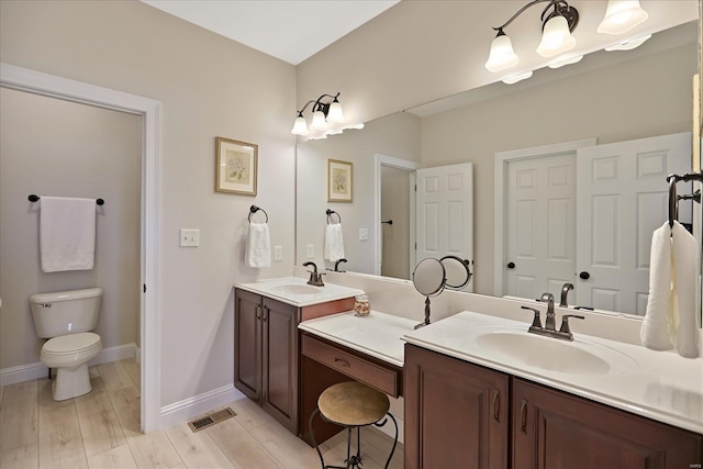 bathroom featuring visible vents, toilet, wood finished floors, baseboards, and vanity