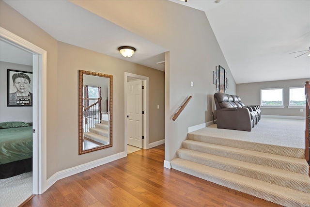 interior space with ceiling fan, lofted ceiling, baseboards, and wood finished floors