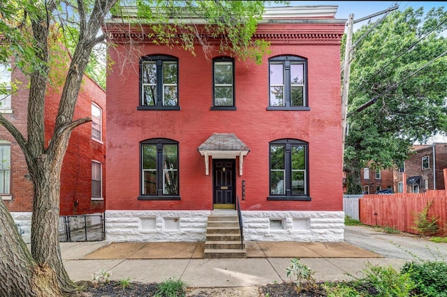 view of front facade featuring brick siding and fence