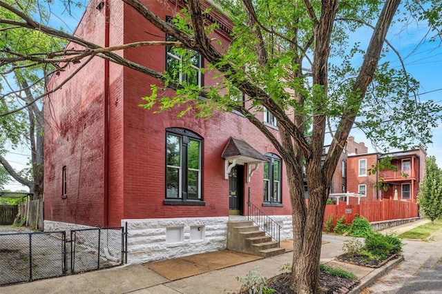 view of front of property with brick siding and fence