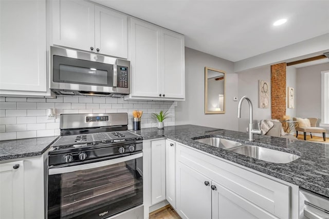 kitchen featuring a sink, stainless steel appliances, white cabinets, and dark stone countertops