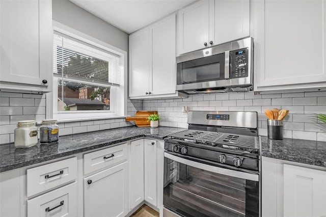 kitchen featuring dark stone countertops, backsplash, appliances with stainless steel finishes, and white cabinetry