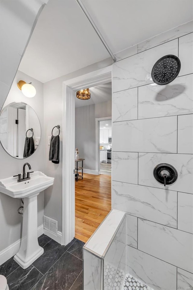 full bathroom featuring a tile shower, visible vents, marble finish floor, and baseboards