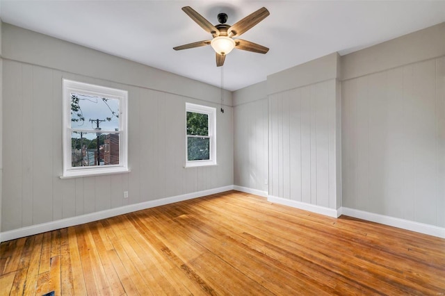 spare room with baseboards, wood-type flooring, and ceiling fan