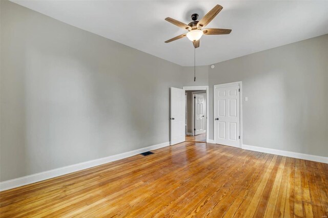 empty room featuring light wood-style flooring, visible vents, baseboards, and ceiling fan