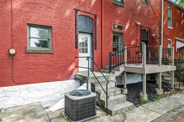 entrance to property featuring brick siding and central AC unit