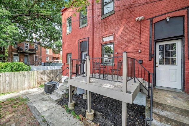 view of exterior entry featuring brick siding and cooling unit