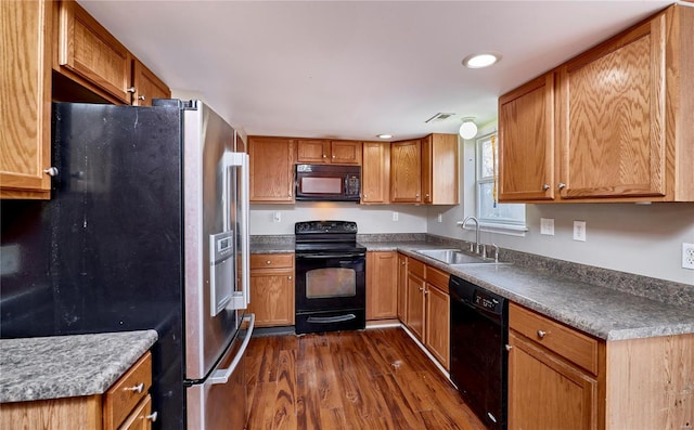 kitchen with visible vents, dark wood-type flooring, brown cabinets, black appliances, and a sink