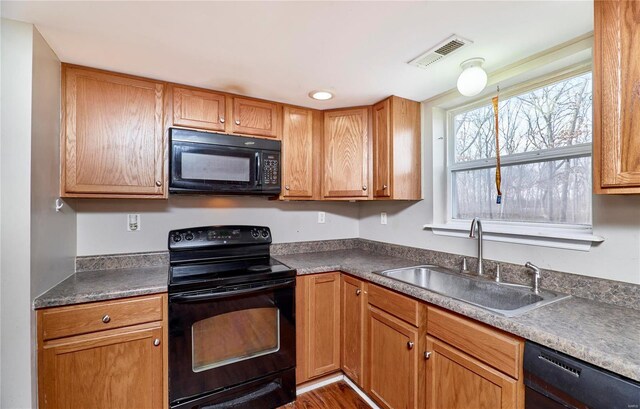 kitchen featuring dark countertops, visible vents, black appliances, and a sink