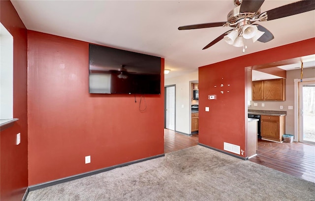 unfurnished living room with visible vents, ceiling fan, carpet, and wood finished floors