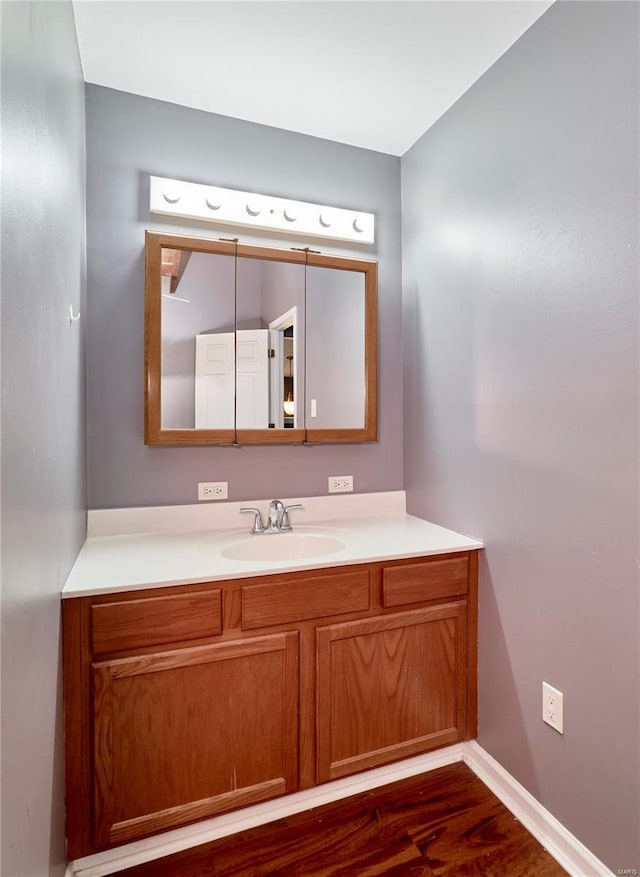 bathroom with baseboards, wood finished floors, and vanity