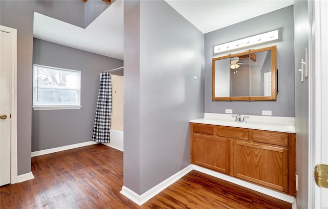 bathroom with shower / bath combination with curtain, vanity, baseboards, and wood finished floors