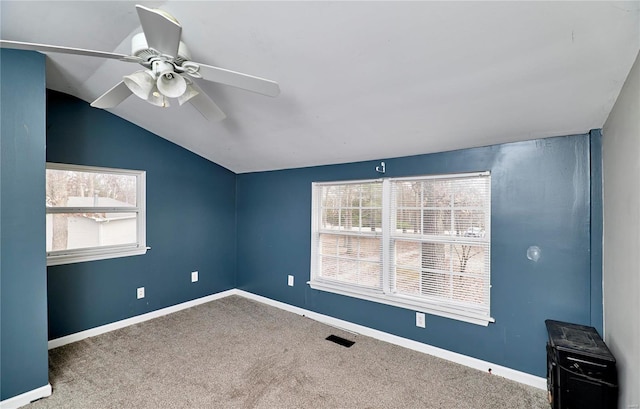 carpeted empty room featuring visible vents, a ceiling fan, baseboards, and vaulted ceiling