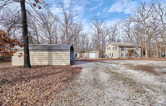 exterior space with a detached garage, an outbuilding, and gravel driveway