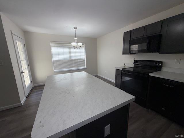 kitchen featuring pendant lighting, black appliances, light countertops, dark cabinets, and dark wood-style flooring