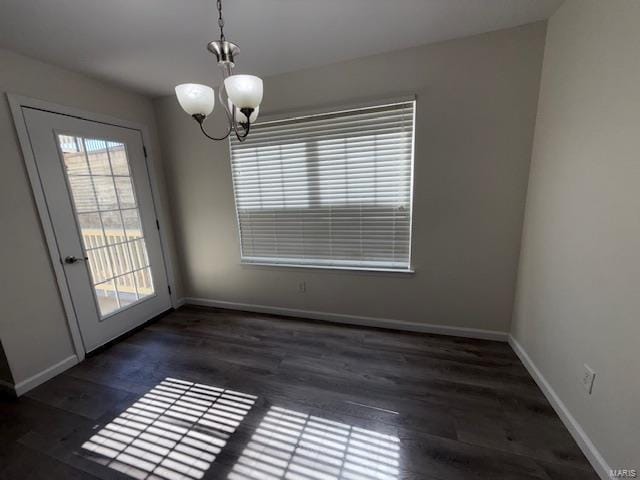 unfurnished dining area with a notable chandelier, baseboards, and wood finished floors