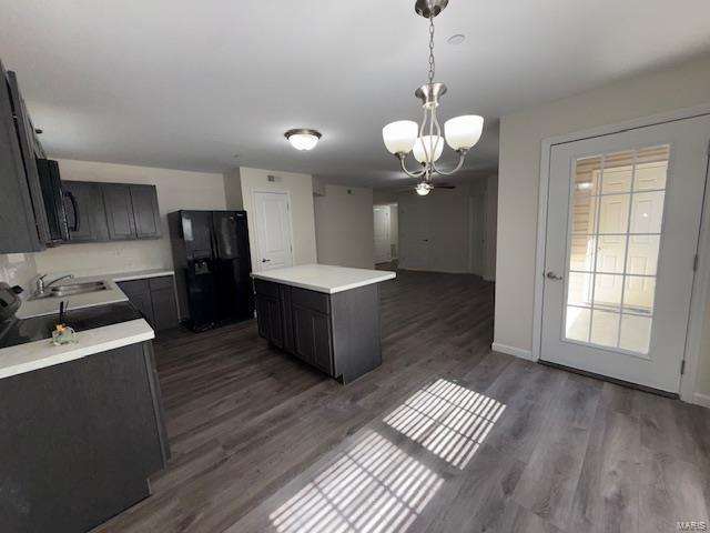 kitchen featuring a kitchen island, black appliances, dark wood finished floors, and light countertops