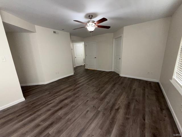 unfurnished living room with baseboards, a ceiling fan, and dark wood-style flooring