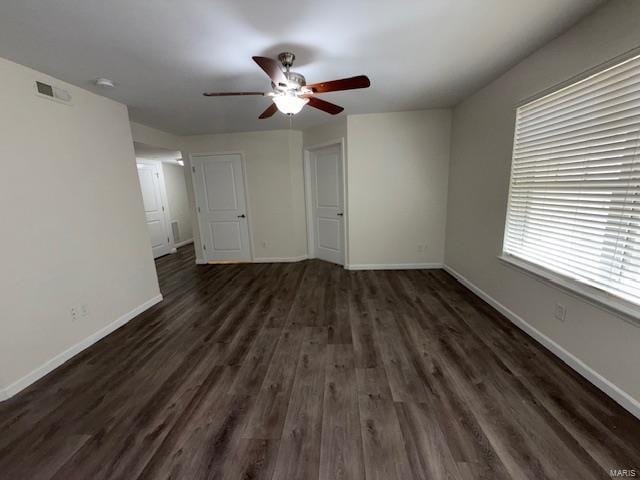 interior space featuring a ceiling fan, dark wood-type flooring, visible vents, and baseboards