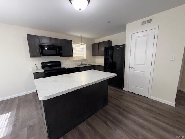 kitchen with visible vents, a kitchen island, black appliances, and light countertops