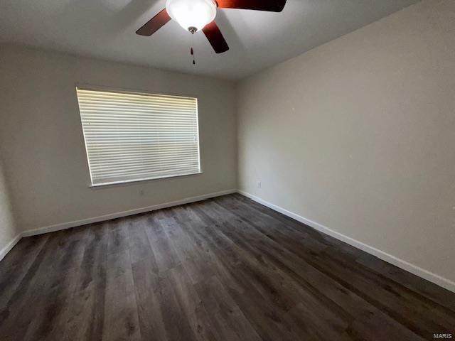 spare room featuring a ceiling fan, dark wood-type flooring, and baseboards