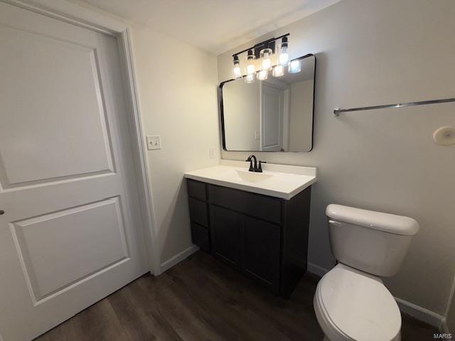 bathroom featuring toilet, vanity, baseboards, and wood finished floors