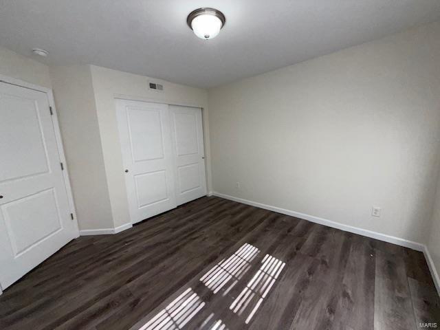 unfurnished bedroom featuring a closet, visible vents, baseboards, and wood finished floors