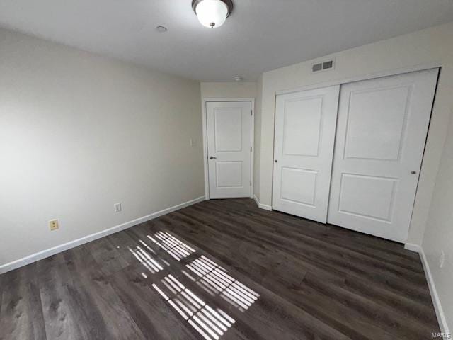 unfurnished bedroom with wood finished floors, visible vents, a closet, and baseboards