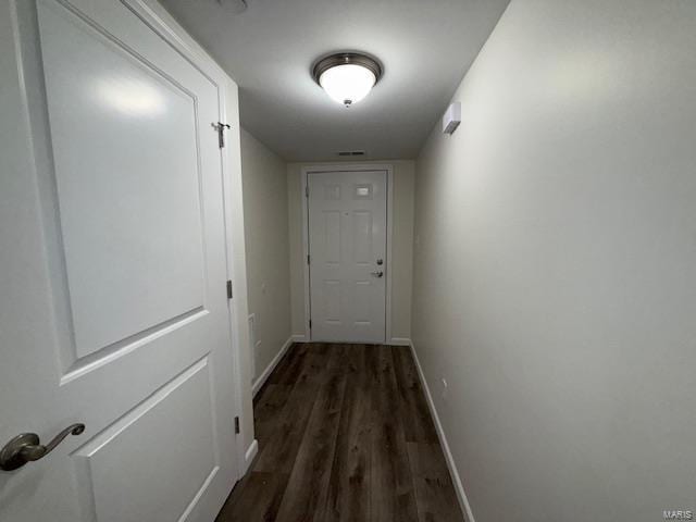 hallway with visible vents, baseboards, and wood finished floors