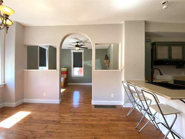 interior space with a ceiling fan, wood finished floors, arched walkways, and a sink