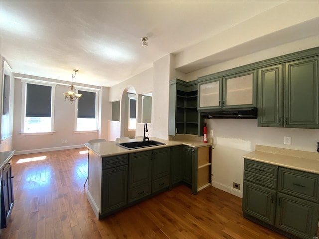 kitchen featuring dark wood-type flooring, arched walkways, green cabinetry, and a sink