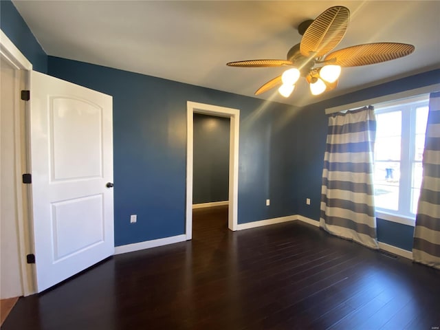 empty room with a ceiling fan, visible vents, wood finished floors, and baseboards