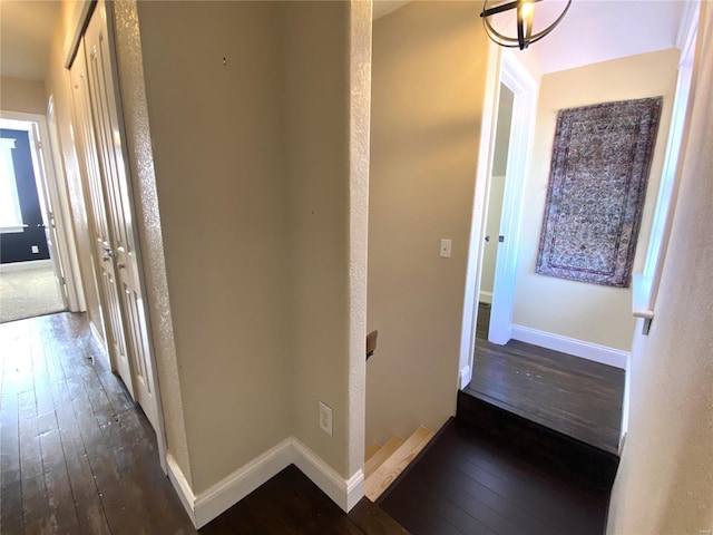 hall with an upstairs landing, baseboards, and hardwood / wood-style floors