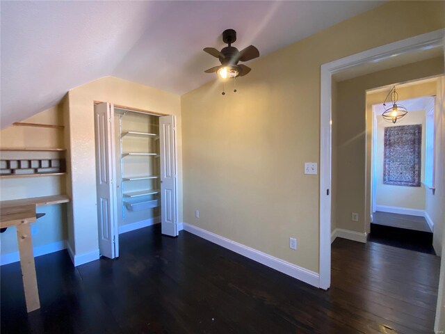 unfurnished bedroom featuring baseboards, lofted ceiling, dark wood-style flooring, ceiling fan, and a closet