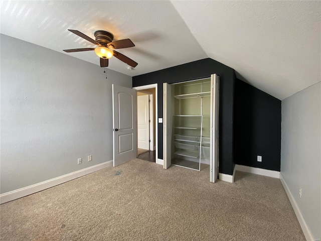 unfurnished bedroom featuring baseboards, lofted ceiling, ceiling fan, a textured ceiling, and light colored carpet