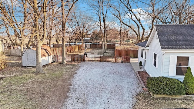 view of yard featuring a storage shed, fence private yard, and an outbuilding