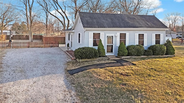 view of front of property with a shingled roof, gravel driveway, a front yard, and fence