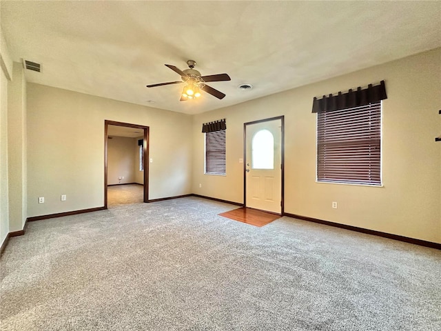 carpeted empty room with visible vents, ceiling fan, and baseboards