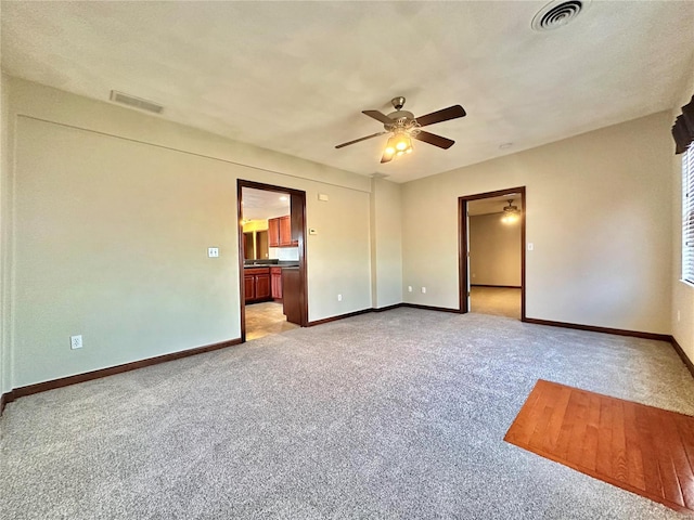 unfurnished room featuring baseboards, visible vents, and light carpet