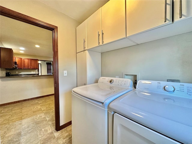 clothes washing area with washer and clothes dryer, cabinet space, and baseboards