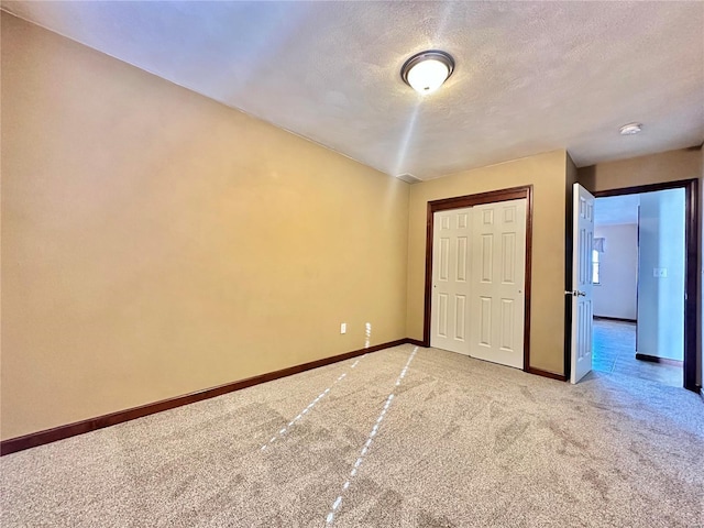 unfurnished bedroom with a closet, baseboards, light colored carpet, and a textured ceiling