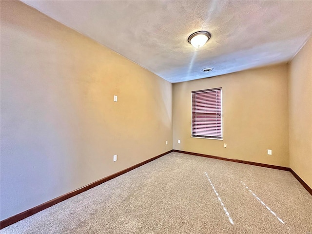 carpeted spare room featuring visible vents, a textured ceiling, and baseboards