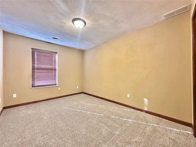 carpeted empty room featuring baseboards, visible vents, and a textured ceiling